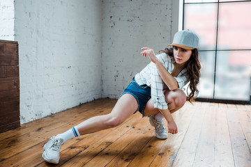 attractive dancer with crossed arms dancing hip-hop in dance studio
