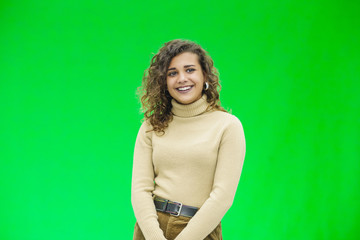 Glowing girl posing on green background, looking positive, smiling.