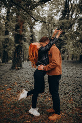 Fototapeta premium Romantic vacation of a guy and a girl in the autumn park. Fun games of a young couple in nature.