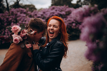 Romantic holidays for a guy and a girl in a spring park. Meeting a young couple in a lilac garden....