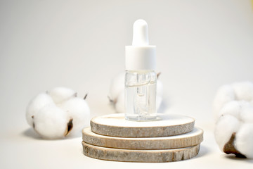 Fototapeta na wymiar A bottle of cosmetic oil and natural cotton on a wooden platform. The concept of natural cosmetics. Place, background for cosmetics. Top view.