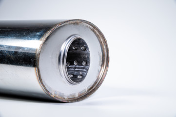 Close-up of the inlet of a new muffler for a car made of stainless steel on a gray background