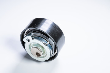 Tension roller of a timing belt of an internal combustion engine on a gray background. The concept of new spare parts and maintenance of vehicles