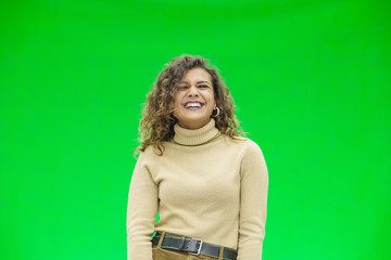 Happy young woman with a cute grin standing on green background with copy space.