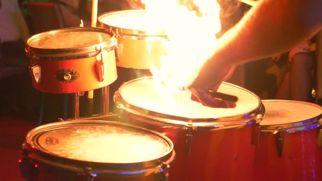 A drummer in a stage costume plays drums in a night club in neon light sometimes with lighted sticks
