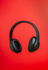 Fototapeta na wymiar Black headphones on a red background. Minimal concept.