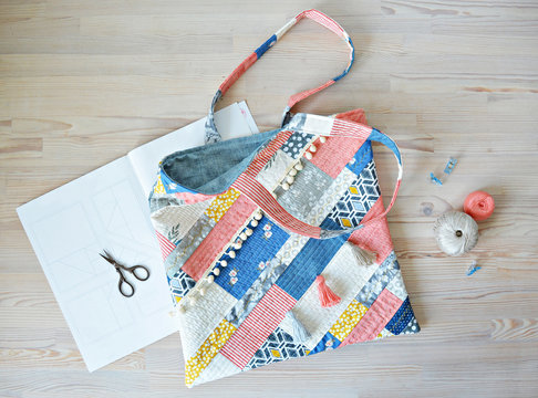  Quilted boho tote bag, scissors, clips and thread on the wooden table 