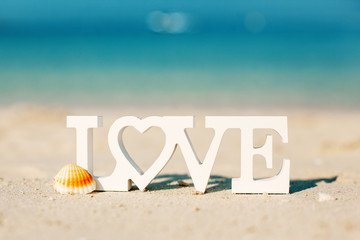 Fototapeta na wymiar Wooden letters love on a sandy beach overlooking the blue sea