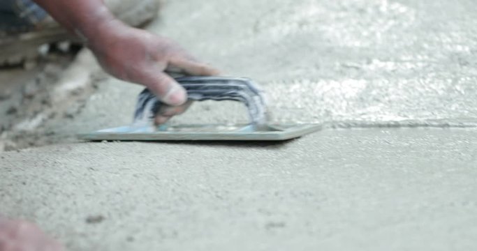 Builder worker smoothing cement at industrial construction work