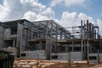 Building and Construction Site in progress. Building construction site against cloudy sky. Metal construction of unfinished building on construction of multi storage building.