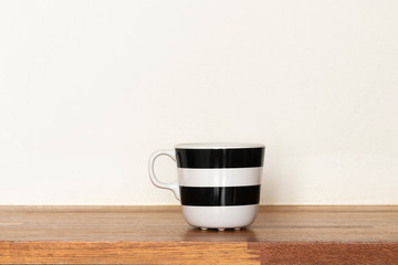 Black and white mugs on wooden shelf.