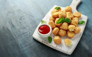 Fried mozzarella, cheddar cheese bites, balls with ketchup on white wooden board