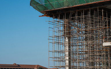 Building and Construction Site in progress. Building construction site against blue sky. Metal construction of unfinished building on construction of multi storage building.
