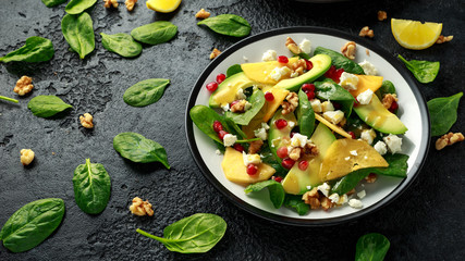 Persimmon, avocado salad with spinach, feta cheese, walnuts and pomegranate seeds. Healthy food.