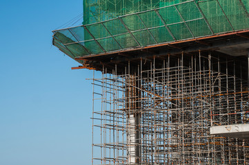 Building and Construction Site in progress. Building construction site against blue sky. Metal construction of unfinished building on construction of multi storage building.
