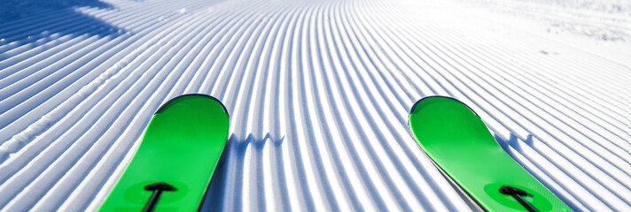 Skis in snow, mountains and ski concept equipments in sunny winter day. Fresh or new groomed slope at best piste resort.