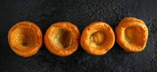 Traditional English Yorkshire pudding side dish on black plate and background