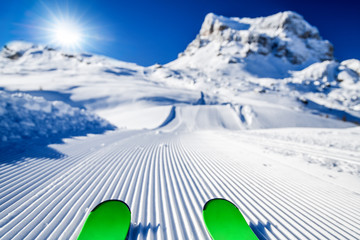 Skis in snow, mountains and ski concept equipments in sunny winter day. Fresh or new groomed slope at best piste resort.
