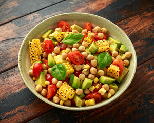 Avocado chickpea salad with grilled sweet corn, tomato and basil. Healthy vegan food