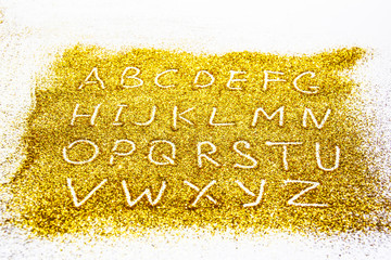 a composition with a capital letters of the alphabet  on beautiful gold glitter. Background and texture of gold glitter. Luxury gold glitter sparkle shining texture background