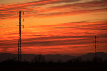 electric towers backlit in a red sunset