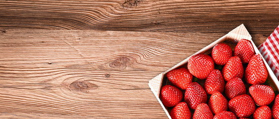 Strawberries in box top view on wooden old rustic table. Beautiful forest juicy strawberry fruits...