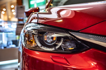 Modern red car headlight close-up.