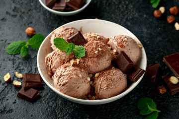 Chocolate Ice Cream with dark chocolate bars and hazelnuts in a white bowl