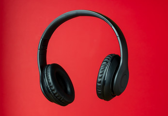 Fototapeta na wymiar Black headphones on a red background. Minimal concept.