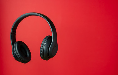Black headphones on a red background. Minimal concept.