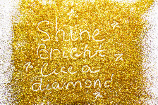 a composition with written a words shine bright like a diamond on beautiful gold glitter. Background and texture of gold glitter. Luxury gold glitter sparkle shining texture background