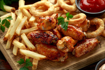 Fried Chicken wings with onion rings, french fries and dipping sauce. take away food.