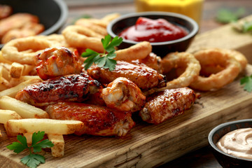 Fried Chicken wings with onion rings, french fries and dipping sauce. take away food.