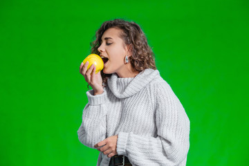 Organic food concept. Smiling female looking at a yellow apple with temptation and geat desire to...