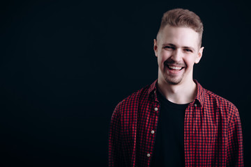 Obraz premium Smiling handsome lad in undone shirt and black t-shirt isolated black background copyspace