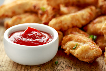 Buttermilk chicken nuggets with ketchup on wooden board