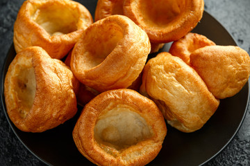 Traditional English Yorkshire pudding side dish on black plate and background