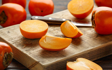 Raw ripe persimmons fruits slices on wooden board