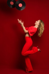 Fototapeta na wymiar Dynamic shot of a young beautiful sexy woman in a red dress dancing on a red background