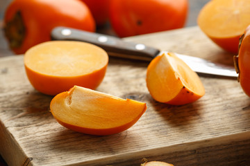 Raw ripe persimmons fruits slices on wooden board