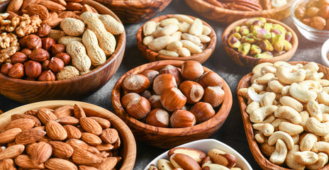 A variety of nuts in wooden bowls from top view. Walnuts, cashew, almond, pistachio, pecan,...