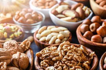 Mix nuts in wooden bowls on dark stone table. Almonds, pistachio, walnuts, cashew, hazelnut.