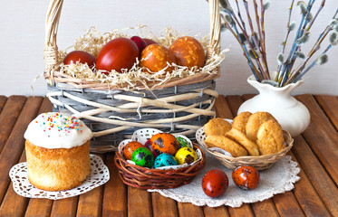 Easter rustic still life with homemade appetizing traditional pastries and a basket of colored...