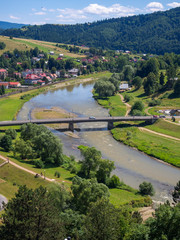 Fototapeta na wymiar Bridge over Poprad river in spa town Muszyna in summer in southern Poland. View from ruins of castle on Zamczysko mountain.