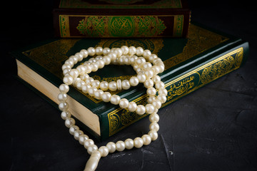 Faith in Islam concept. The Islamic holy book, Quran or Kuran, with rosary beads or “tasbih” on dark background.