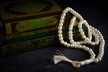 Faith in Islam concept. The Islamic holy book, Quran or Kuran, with rosary beads or “tasbih” on...