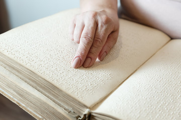 woman reading braille text on old book