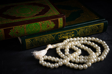 Faith in Islam concept. The Islamic holy book, Quran or Kuran, with rosary beads or “tasbih” on...