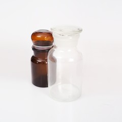 Brown and transparent glass jars for laboratory medical research isolated on white background.