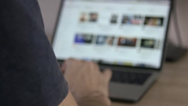 Man scrolling YouTube main page feed on notebook blurred